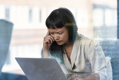 Thoughtful woman with frown forehead using laptop