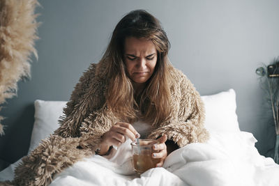 Portrait of a young woman drinking glass at home