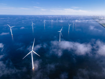 Low angle view of wind turbines against sky