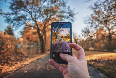 Close-up of hand holding mobile phone in park