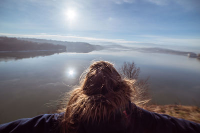 Rear view of woman looking at lake against sky