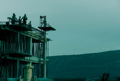 Low angle view of silhouette cranes against sky at dusk