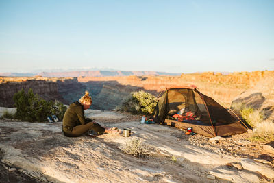 Female camper prepares food next to campsite overlooking grand canyon