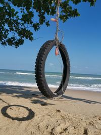 Close-up of rope on beach by sea against sky