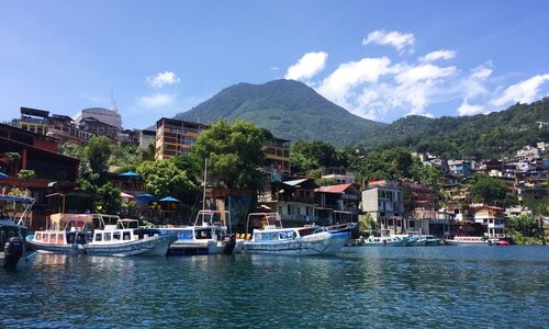 Sailboats in city by buildings against sky