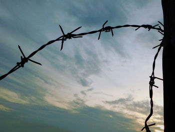 Low angle view of barbed wire against sky