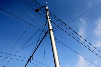 Low angle view of electricity pylon against blue sky