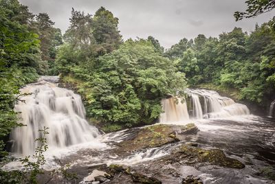 Scenic view of waterfall against trees