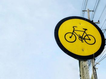 Low angle view of yellow sign against sky