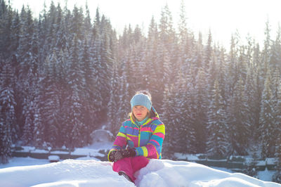 Portrait of woman sitting on snow covered field during winter