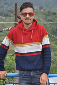 A handsome indian young guy wearing sunglasses, standing outdoor with looking at camera 