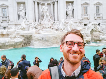 Portrait of man with statue in front of building