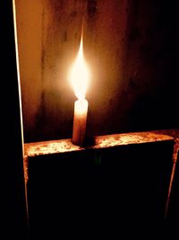 Close-up of lit candle in dark room