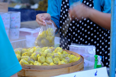 Midsection of woman holding food at market stall