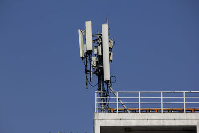 Low angle view of communications tower against clear blue sky