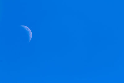 Low angle view of moon against clear blue sky