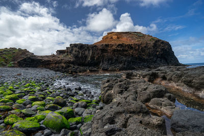 Rock formations on shore against sky