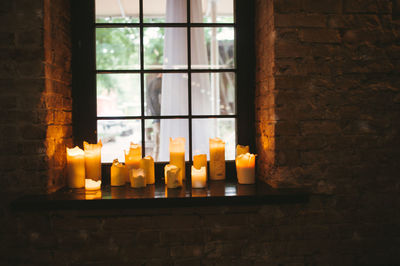 Close-up of burning candles on window sill