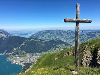 Wooden cross on top of mountain against blue sky