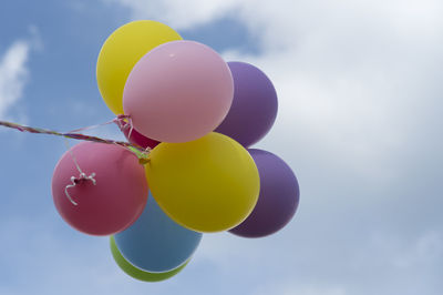 Low angle view of colorful balloons flying against cloudy sky