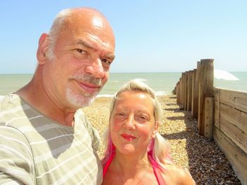 Portrait of smiling couple on beach against sky