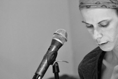 Close-up of young woman with microphone against wall