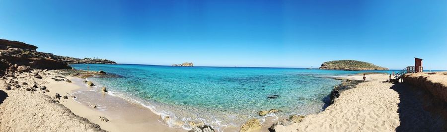 Panoramic view of beach against clear blue sky