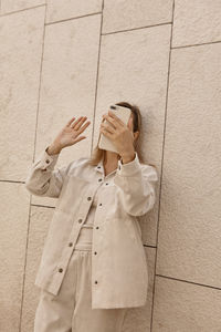 Young woman standing against wall