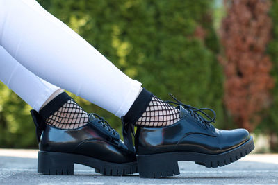 Low section of woman wearing shoes on footpath