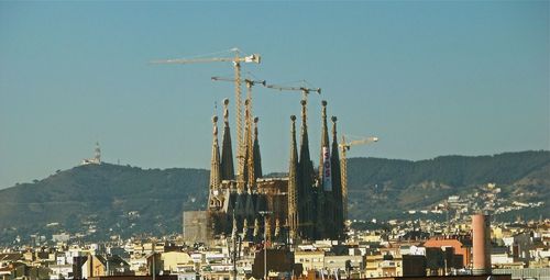 Cranes against buildings in city against clear sky