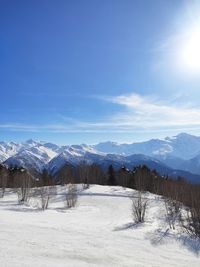 Scenic view of snow covered mountains against blue sky