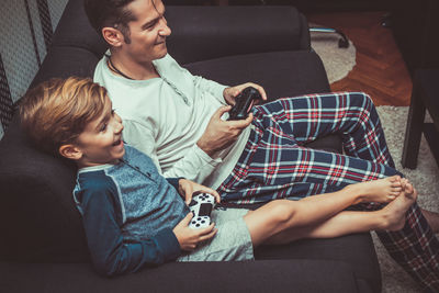 Father and son playing video game on sofa at home