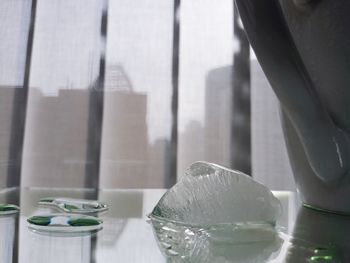 Close-up of glass on table against window at home