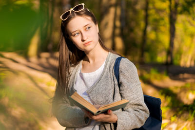 Young woman reading book while standing outdoors