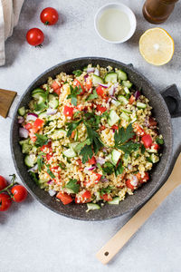 Vegetable and bulgur salad in bowl on table decorated with food and kitchen utensils