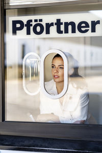 Thoughtful woman looking through window at porter's lodge