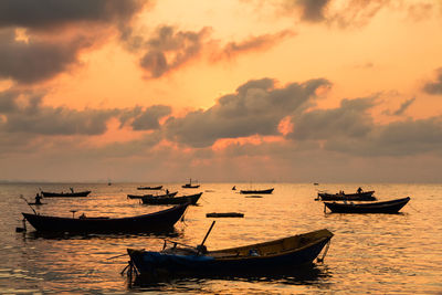 Boats in sea at sunset