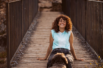 Portrait of young woman sitting on footbridge