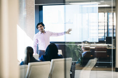 Businessman giving presentation in meeting seen through window