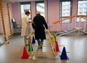 Physical therapist assisting senior man in exercising at nursing home