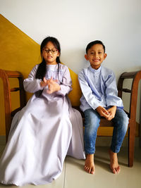 Siblings sitting on bench at home during eid-ul-fitr