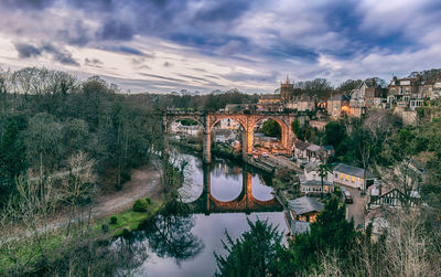 Bridge over river in city against sky