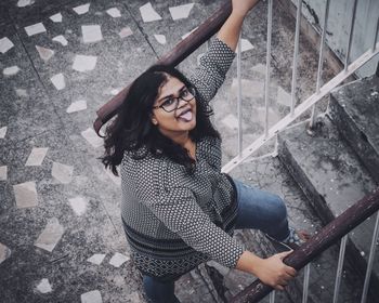 High angle view portrait of young woman standing on staircase