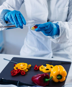 Midsection of scientist experimenting on bell peppers