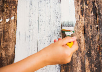 Cropped image of person painting wooden planks