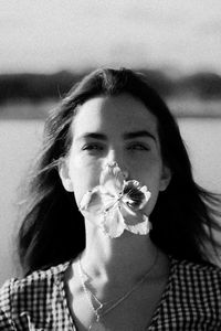 Close-up of young woman carrying flower in mouth