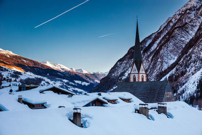 Panoramic view of building and snowcapped mountains against sky