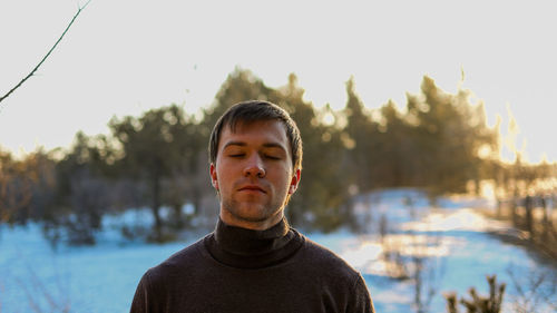 Portrait of young man against trees