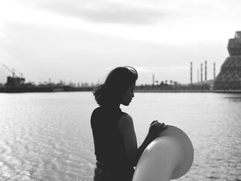 Portrait of young woman standing against lake