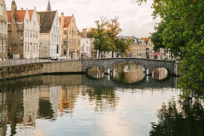 Bridge over river by buildings against sky in city